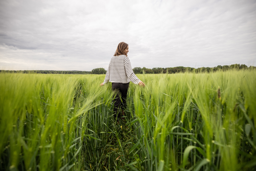 Woman walking through field of waist-high grass