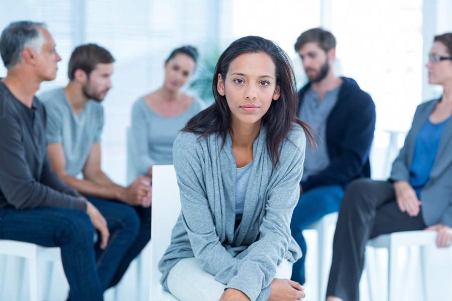 Woman facing out from a session of group therapy for addiction