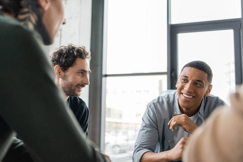 Two men smiling within a session of group therapy for addiction