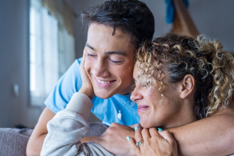 Mother embracing son who is embracing her from behind