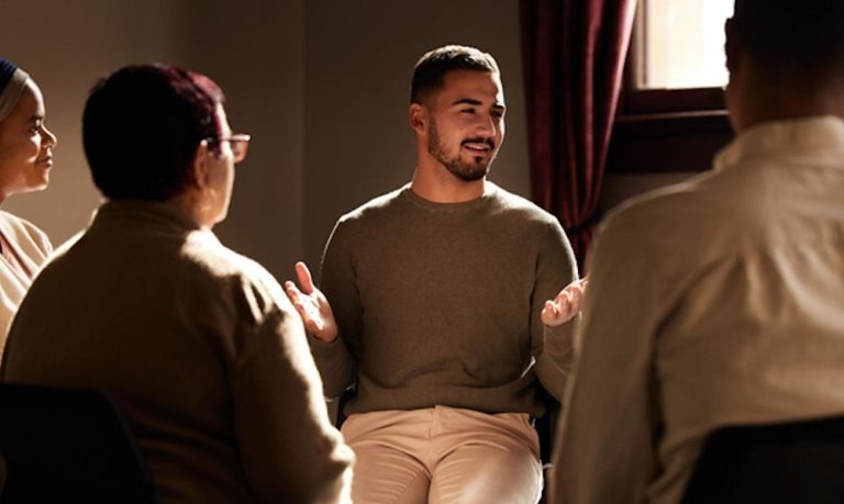 a man with both hands up while talking with the group 