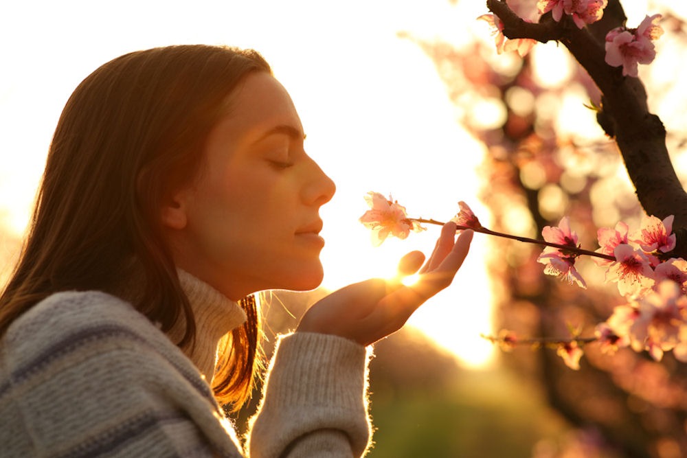 Woman bending to smell flower on narrow stick