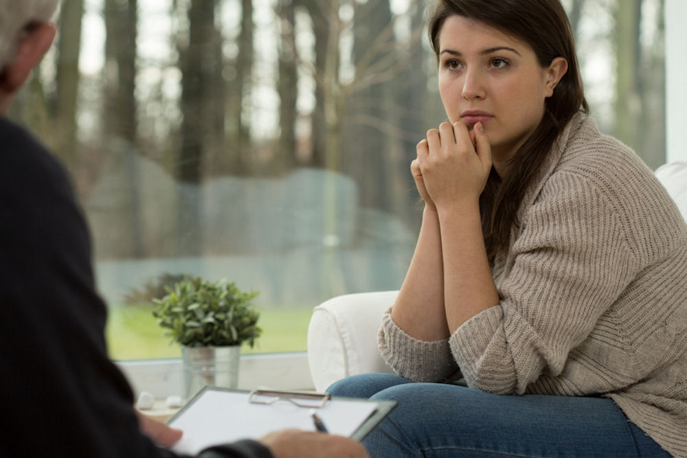 Woman listens to therapist describing PTSD and addiction