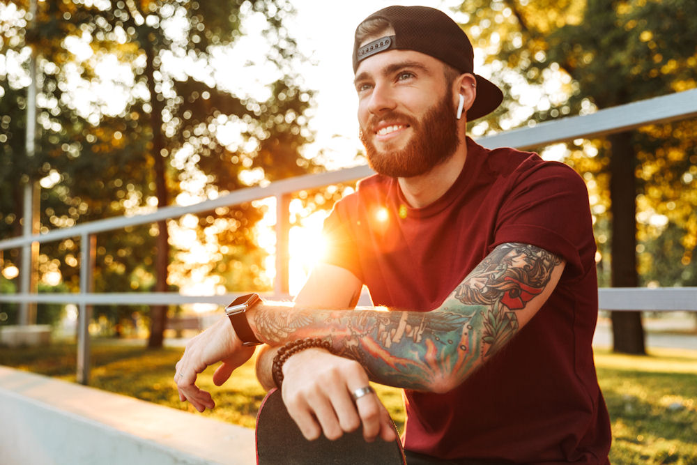 Attractive cheerful young man sitting at the skate park ramp Man who found a way to stop binge drinking
