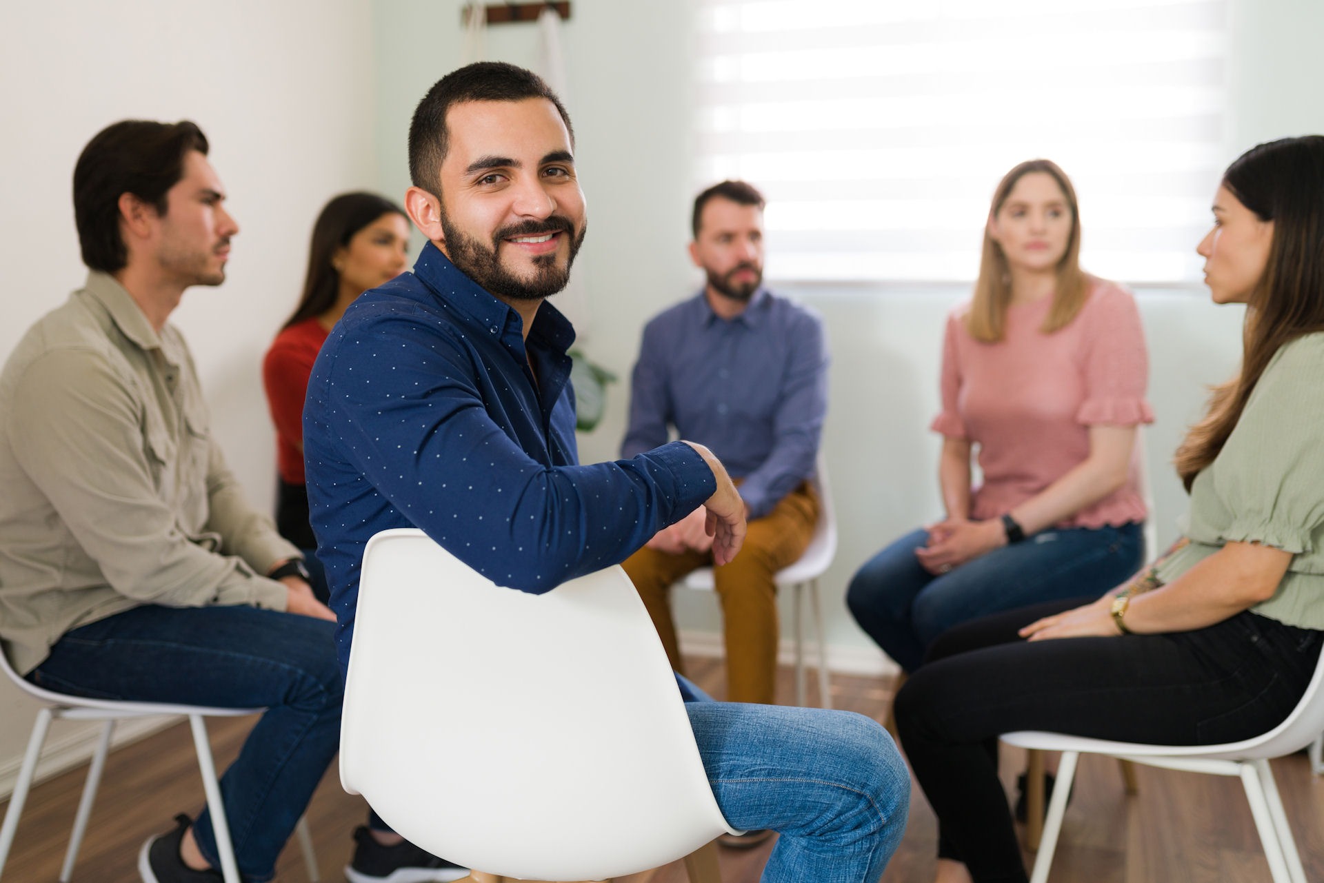 healthy-routines-life-after-rehab man looking over shoulder and smiling during group therapy