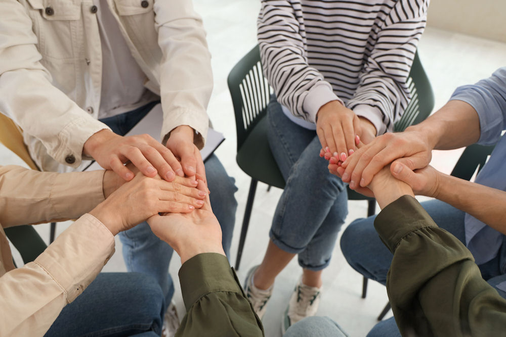 members of an addicted family holding hands during a therapy session