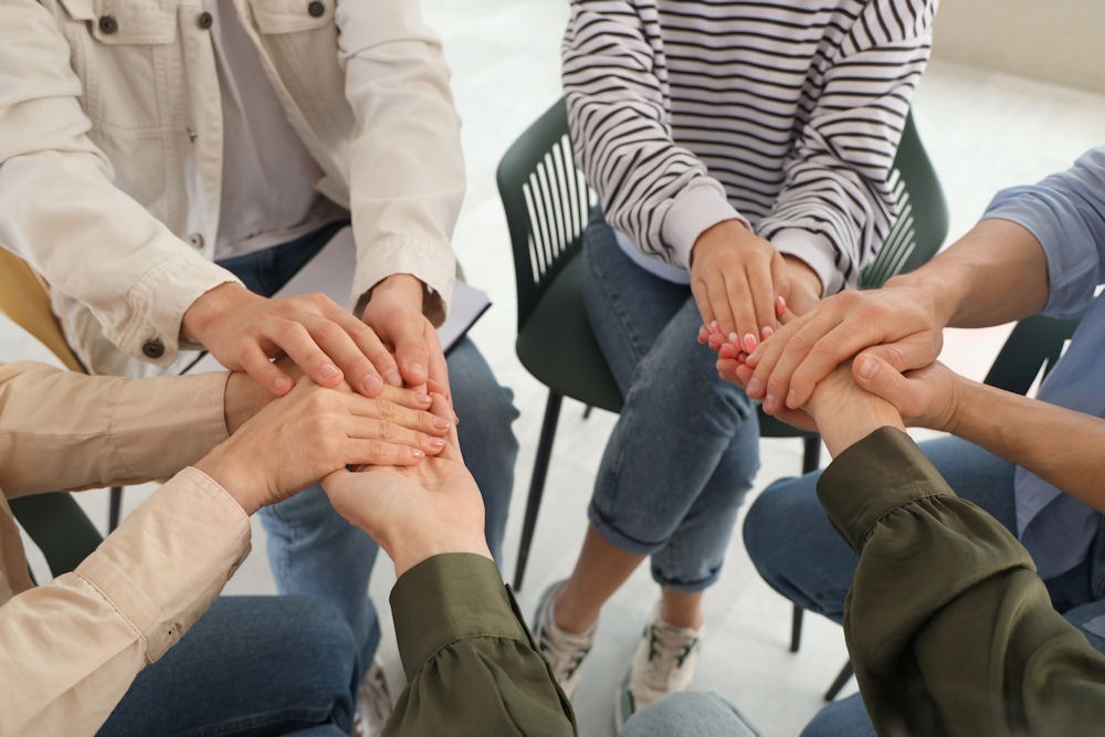 members of an addicted family holding hands during a therapy session