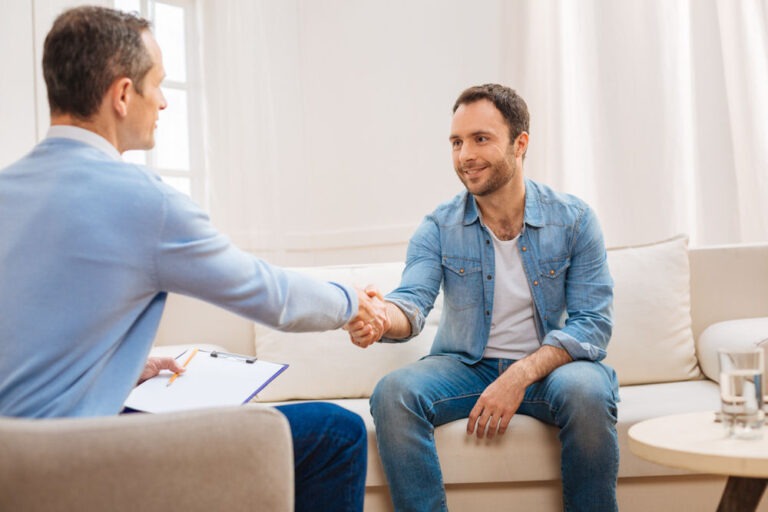 dna-role-in-mental-health-disorders man sitting on a couch and shaking his therapist's hand