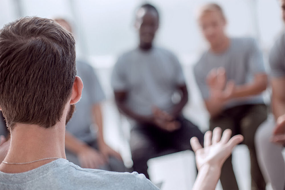 man talking to peers during a group therapy session