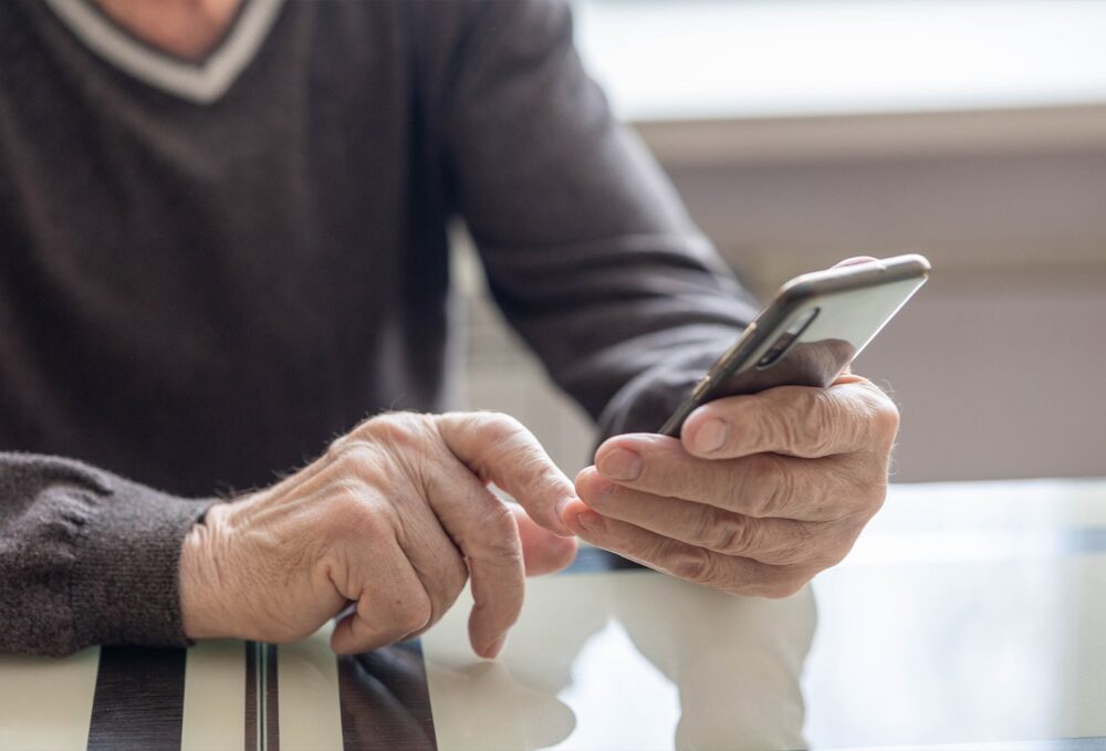 Person alone checking their phone, illustrating behavioral warning signs of isolation and substance use.