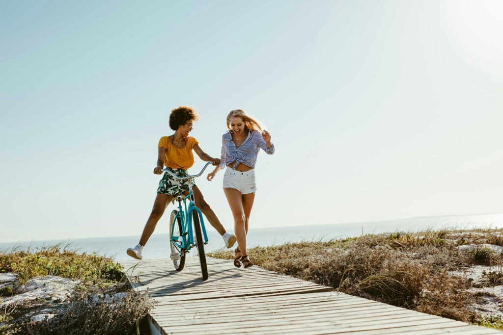 Young adult women walking and biking along a quiet New Jersey beach at sunrise during sober recovery