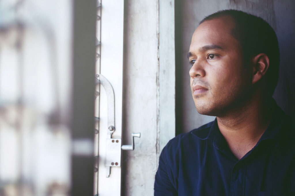 Person sitting quietly by a window reflecting on psychological dependence and mental health recovery.
