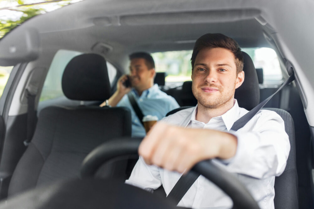 smiling man driving car with an instructor in the backseat for IDRC