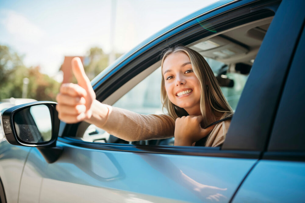 smiling woman putting a thumbs up out her car window after completing impaired driver rehabilitation course in New Jersey