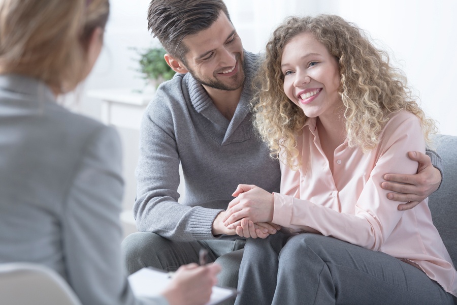 Woman smiling while being hugged by partner during addiction treatment.