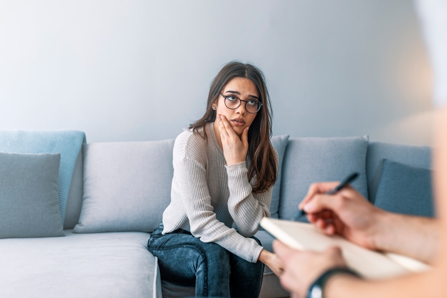a woman with hand on face sitting on couch